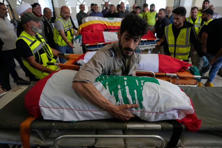 A paramedic volunteer lays the body one of the six family members on a stretcher after they were killed on Wednesday when their car was struck in an Israeli airstrike on a highway as they fled their village, during a funeral procession in the southern port city of Tyre, Lebanon, Friday, May 29, 2026. (AP Photo/Mohammed Zaatari)