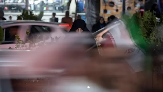 في 22 مايو/أيار 2026، لوّحت إحدى مؤيدات الحكومة، وهي ترتدي النقاب، بالعلم الإيراني خلال مسيرة ليلية في منطقة تجارية بوسط طهران. وكان الرئيس الأمريكي دونالد ترامب قد هدد إيران باحتمال نشوب صراع جديد. ووفقاً لتقارير رسمية، يدرس ترامب اتخاذ إجراء عسكري ضد الجمهورية الإسلامية في حال عدم التوصل إلى اتفاق مع المسؤولين الإيرانيين.