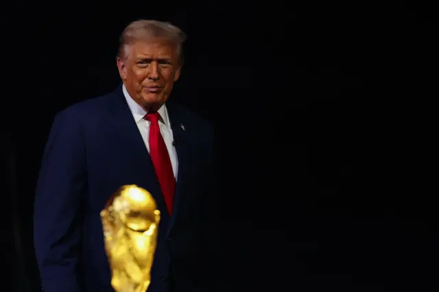 الرئيس الأمريكي دونالد ترامب يقف قرب كأس العالم، بينما حذرت "ذا ميرور" من أن سياسات الدخول إلى الولايات المتحدة قد تحول البطولة من حدث رياضي جامع إلى رمز للانقسام.