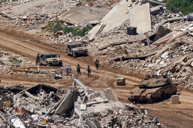 TOPSHOT - This photograph taken from the northern Israel shows Israeli tanks and military vehicles standing along the road between destroyed houses in southern Lebanon near the border with Israel, on April 29, 2026. Lebanon's army said on April 29 that one of its soldiers was among two people killed in an Israeli strike in the country's south, the latest deadly raid despite a ceasefire in the Israel-Hezbollah war. (Photo by Jalaa MAREY / AFP via Getty Images)