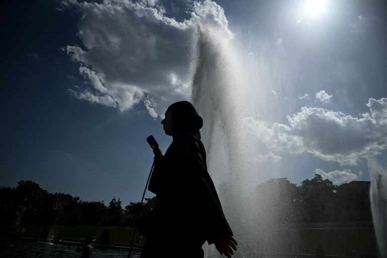 A pedestrian holding a fan walks by the Trocadero Fountain during a heatwave in Paris on June 22, 2026.