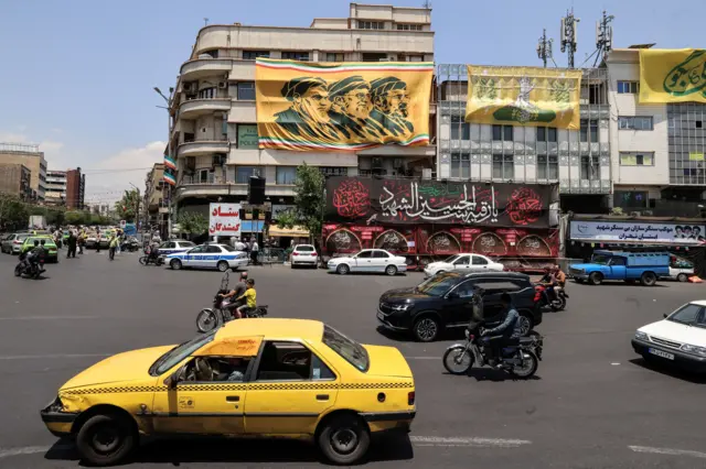 مارة يقودون سياراتهم قرب لافتة في طهران تُظهر المرشد الإيراني الراحل روح الله الخميني، وخليفته الراحل علي خامنئي، والمرشد الجديد مجتبى خامنئي، في 3 يونيو/حزيران 2026، بالتزامن مع تحذيرات إيرانية من مزيد من الضربات الصاروخية وبالطائرات المسيّرة إذا جددت الولايات المتحدة هجماتها على إيران.