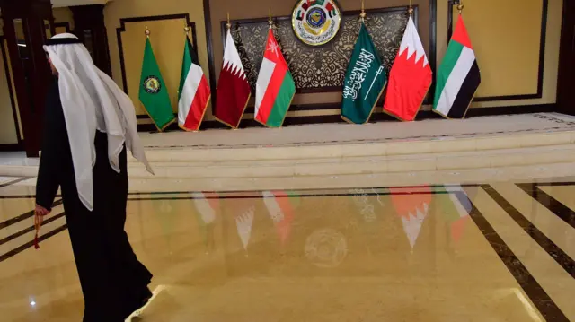 رجل يمرّ أمام أعلام الدول المشاركة في قمة مجلس التعاون الخليجي في قصر بيان بمدينة الكويت، بتاريخ 5 ديسمبر/كانون الأول 2017.
