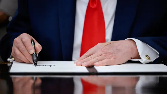 صورة تُظهر يدي الرئيس الأمريكي دونالد ترامب بينما يوقّع على إعلان لاستعادة الصيد التجاري الأمريكي في المحيط الهادئ، في المكتب البيضاوي للبيت الأبيض.