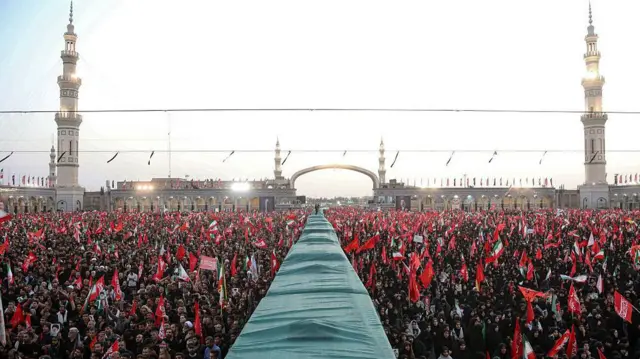 حشود المشيعين في باحة مسجد جمكران في قم في إيران يحملون رايات حمراء وأعلام إيران - جنازة علي خامنئي -