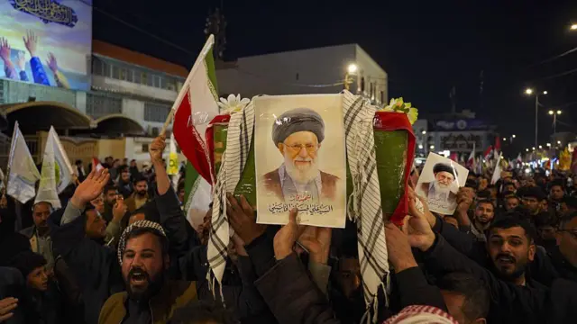 في موكب تشييع رمزي في العراق ليلاً، يحمل حشد أعلاماً وصوراً للمرشد الأعلى الإيراني السابق آية الله علي خامنئي.