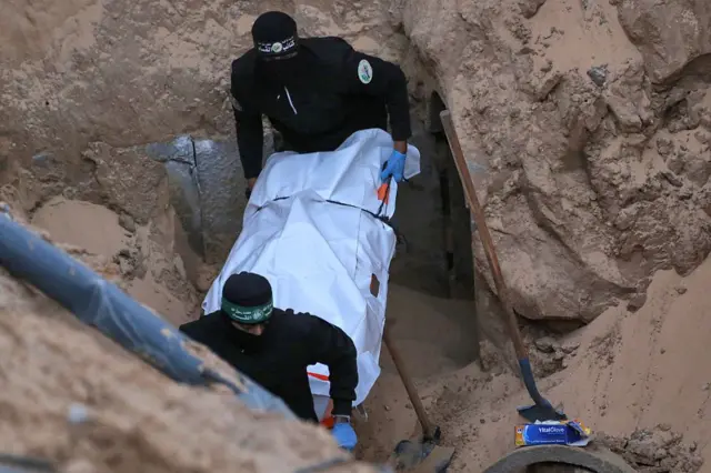 مسلحون من حركة حماس يحملون جثماناً تم انتشاله من نفق بمنطقة شمال خان يونس، جنوب قطاع غزة، في 28 أكتوبر/تشرين الأول عام 2025، وهو واحد من 28 رهينة وافقت الحركة على تسليمهم بموجب اتفاق وقف إطلاق النار. 