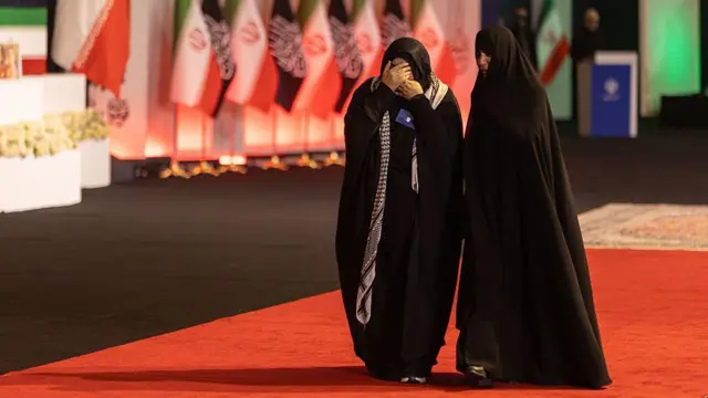 امرأة تغطي وجهها أثناء مرورها أمام توابيت تضم جثمان المرشد الأعلى الإيراني الراحل، آية الله علي خامنئي، وأفراداً من عائلته، في مصلى الإمام الخميني الكبير في طهران، إيران، في الثالث من يوليو/تموز 2026.