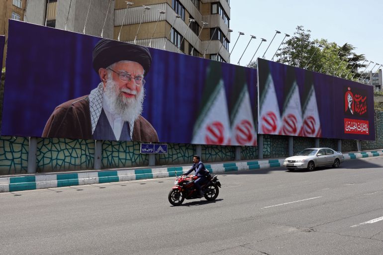 Commuters drive past a giant billboard bearing a picture of Iran's late supreme leader Ayatollah Ali Khamenei ahead of his funeral, in Tehran on July 2, 2026.