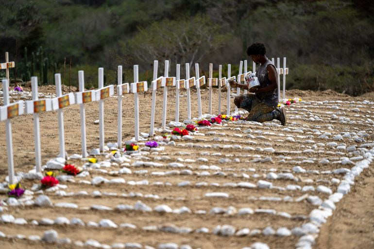 A worker paints graves for unidentified victims of the June 24 earthquake at La Esperanza Cemetery in Catia La Mar, La Guaira state, northeast of Caracas, on July 5, 2026.