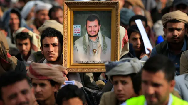 يحمل يمنيّ شيعي صورةً للزعيم الحوثي عبد الملك الحوثي، أثناء استماعه لخطابٍ ألقاه خلال مراسم إحياء ذكرى عاشوراء في صنعاء، بتاريخ 25 يونيو/حزيران 2026.