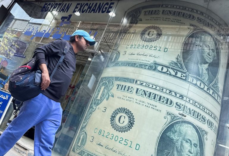 An Egyptian man walks past a currency exchange display showing images of the U.S. dollar, as exchange rates continue to rise against the pound, which climbed above 50 pounds amid the expanding U.S.-Israeli conflict with Iran, in Cairo, Egypt, March 9, 2026. Picture taken with a mobile phone. REUTERS/Amr Abdallah Dalsh 