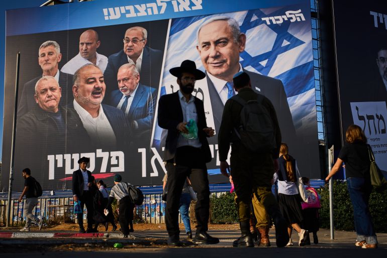 People walk past a Likud party campaign billboard featuring Israeli Prime Minister Benjamin Netanyahu alongside opposition party leaders and bearing the Hebrew slogan "Right or Palestine," ahead of Israel's general election, in Beni Brak, Israel, Sunday, Oct. 18, 2026. (AP Photo/Oded Balilty)
