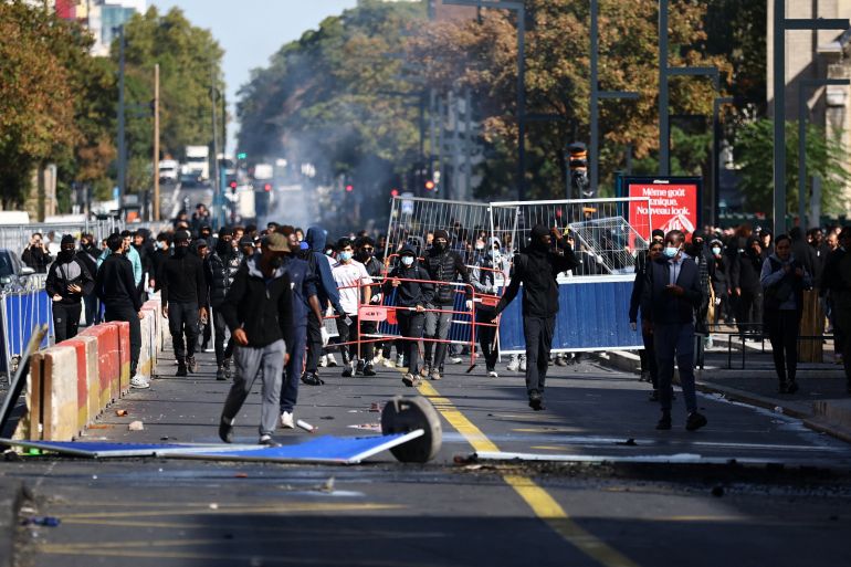 Masked protesters react in a street amid clashes during a protest by high school students near the Lycee Berthelot high school in Aubervilliers near Paris as part of nationwide protests to demand the hiring of substitute teachers, increased resources and better learning conditions, as more than 400 schools remain closed following days of student protests that have escalated into violence in some places, France, October 2, 2026. REUTERS/Sarah Meyssonnier